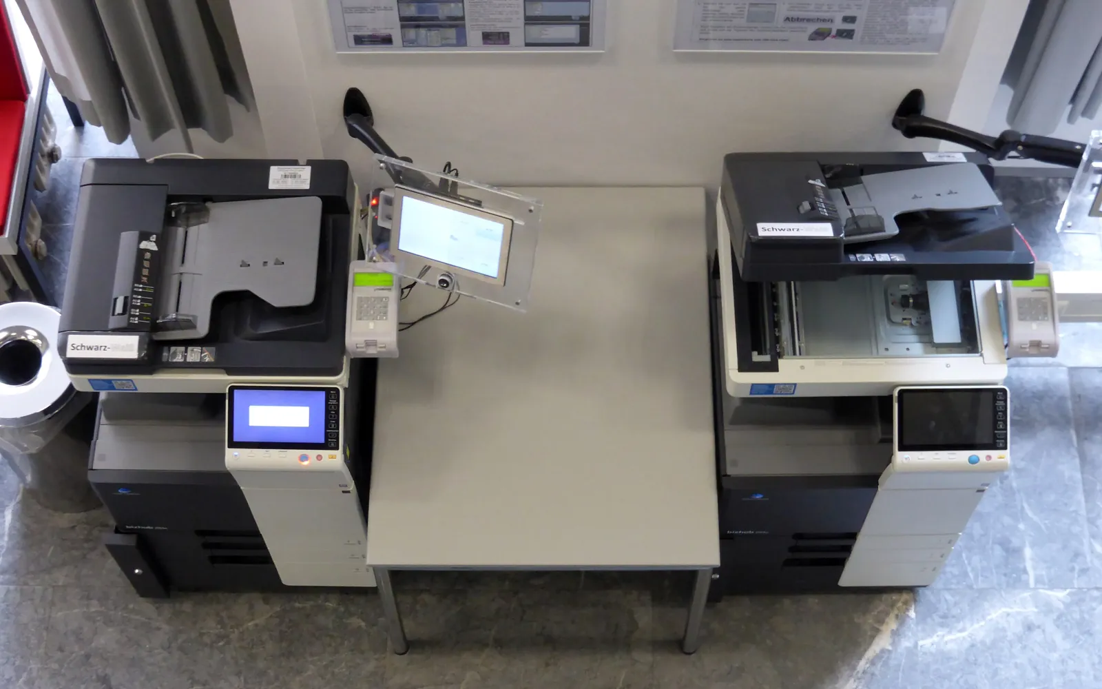 A row of shared copiers and printers in a copy room